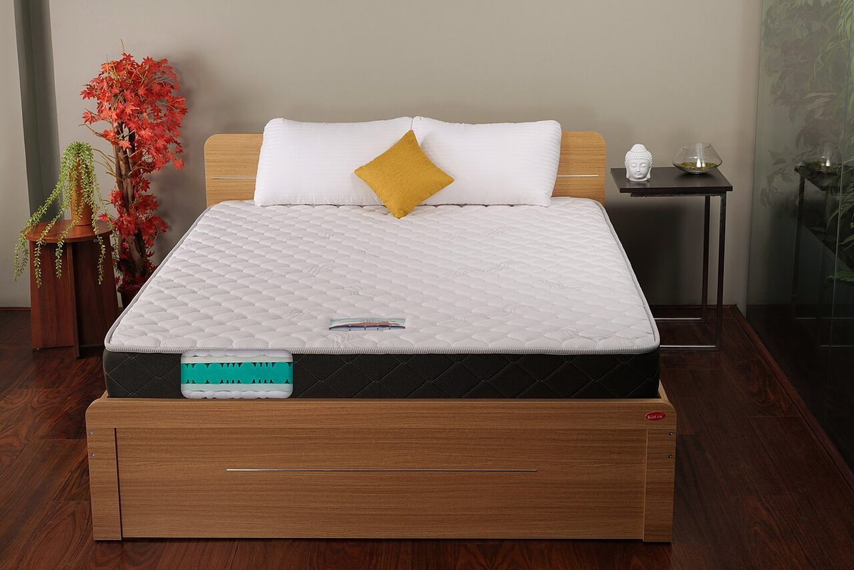 A quilted mattress on a wooden bed frame with pillows and a cushion