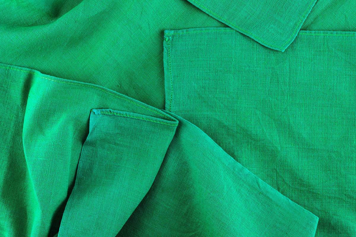 Folded green linen fabric showing its loose, textured weave